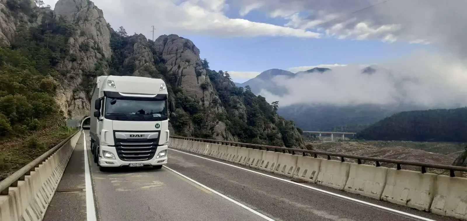 Ein weißer DAF-Lkw von HT Logistics auf einer Bergstraße